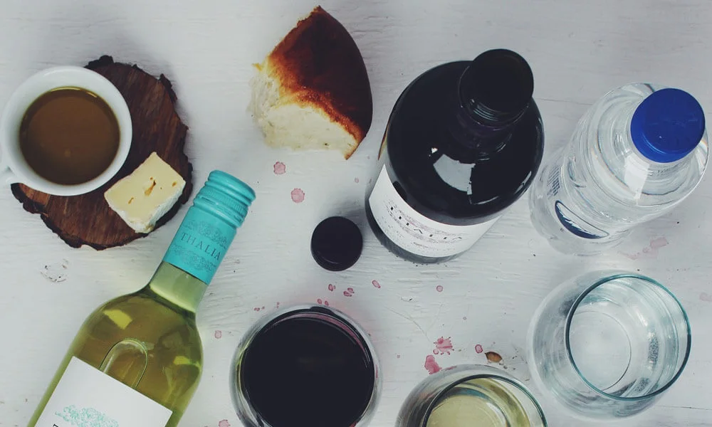 Na sliki so steklenice vina ter šalčke kave, za blog tiščanje v želodcu.